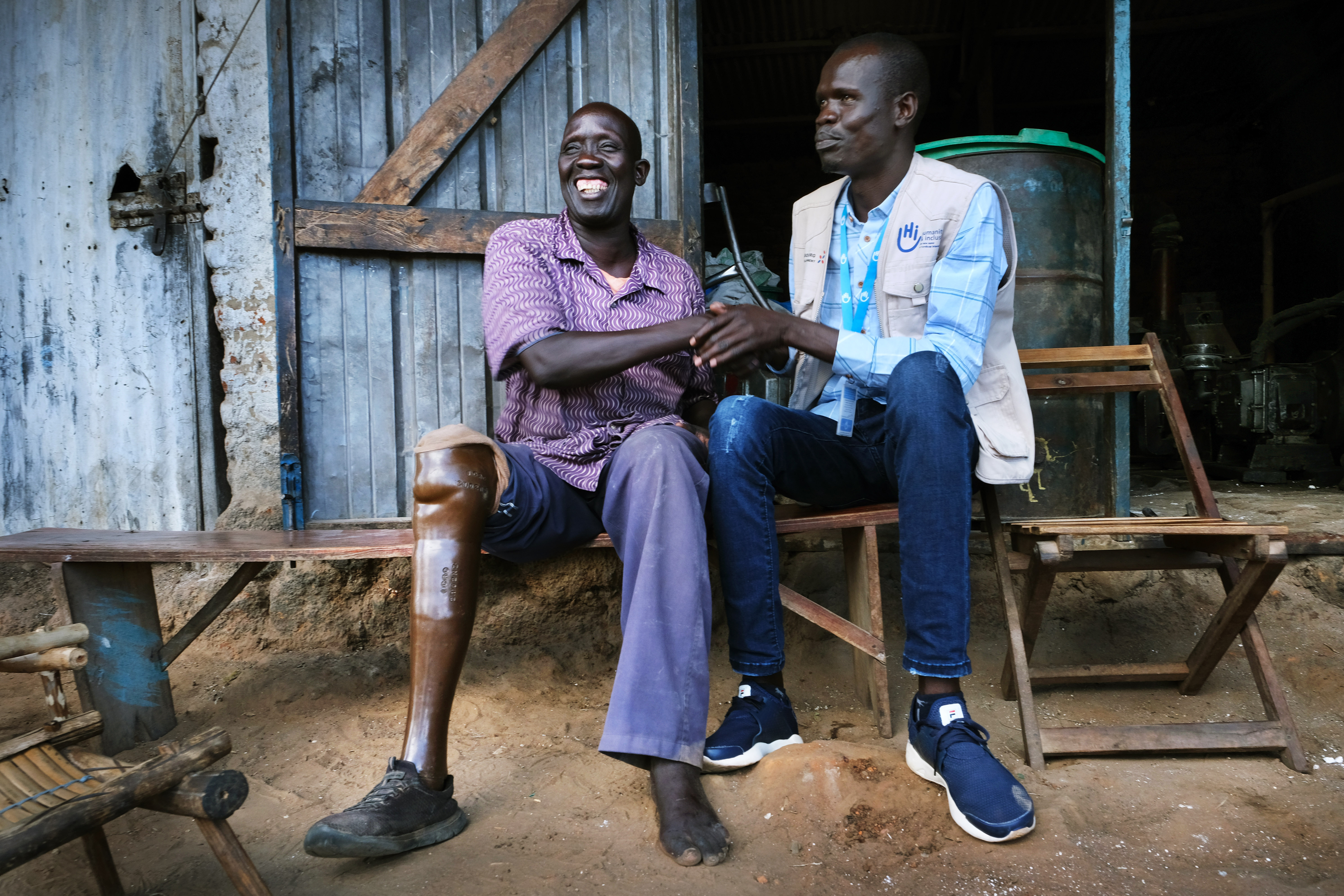An HI staff member sits with Oliver, who lost his leg in a mine accident. 